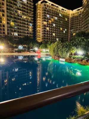 a view of a pool at night with buildings at Azure staycation by scarlet suites in Manila
