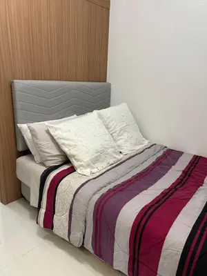 a bed with a striped blanket and pillows on it at Lush Residences 1Br Haven Suite Makati Smart TV Netflix Hi speed internet in Manila