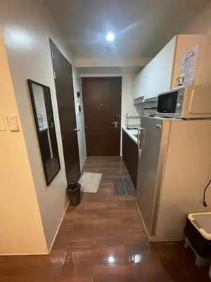 a small kitchen with a refrigerator and a door at Affordable Staycation Home in Makati in Manila