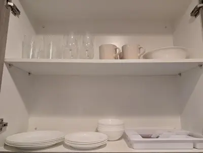 a white shelf with dishes and glasses on it at Cozy Modern Sunset View in Manila