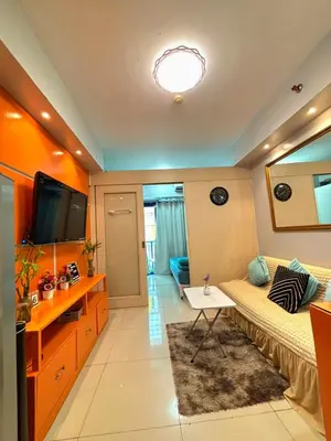 a room with a bed and a tv and a table at Sarah's Staycation at Sea Residences Near Moa in Manila