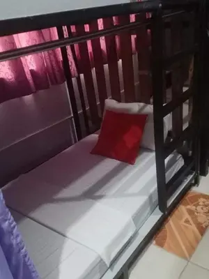 a small bed with a red pillow on it at Sean Lojed Hostel in Manila