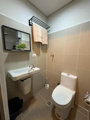 a bathroom with a toilet and a sink and a mirror at Coastresidences by Rinseiki in Manila