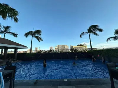 a group of people in a swimming pool with palm trees at Coastresidences by Rinseiki in Manila