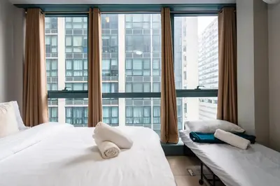 two beds in a room with a large window at One Uptown Residence BGC 2BR Cor unit with balcony ,washer in Manila