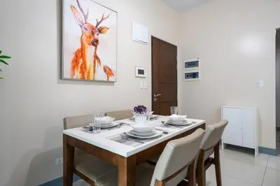 a dining room table with chairs and a painting of a deer at One Uptown Residence BGC 2BR Cor unit with balcony ,washer in Manila
