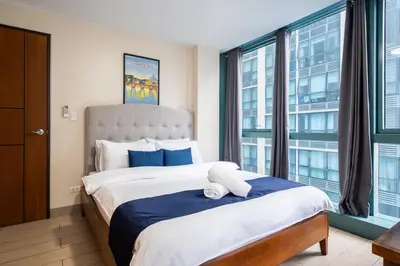 a bedroom with a large bed with a large window at One Uptown Residence BGC 2BR Cor unit with balcony ,washer in Manila