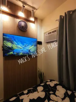 a bedroom with a flat screen tv on a wall at CUBAO Macks Awesome Place NETFLIX UNLIFAST WIFI in Manila