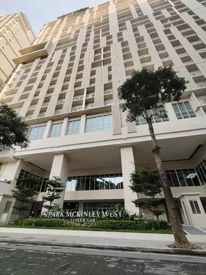 a large building with a tree in front of it at Condo Suite 1 Bedroom McKinley West Taguig City in Manila