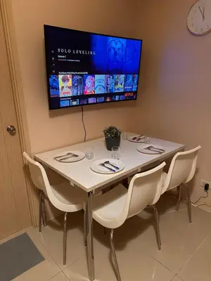 a table with chairs and a tv on the wall at The Essential 2 BR at Sm Jazz makati 100 mbps in Manila
