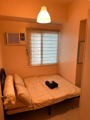 a small bed in a room with a window at The Essential 2 BR at Sm Jazz makati 100 mbps in Manila