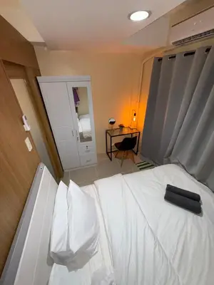 a bedroom with a white bed with a black remote control on it at Spacious pool view at Mall of Asia 100mb Netflix in Manila