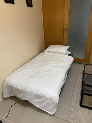 a large white bed in a room with a chair at Spacious pool view at Mall of Asia 100mb Netflix in Manila
