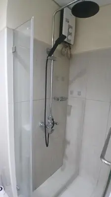 a shower with a glass door in a bathroom at Spacious pool view at Mall of Asia 100mb Netflix in Manila
