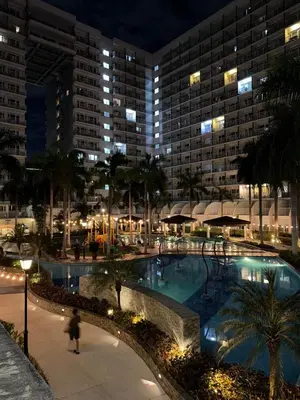 a large swimming pool at a hotel at night at Spacious pool view at Mall of Asia 100mb Netflix in Manila