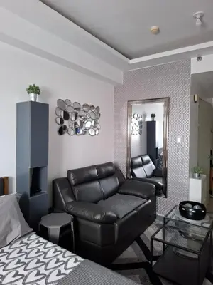 a living room with a leather couch and a mirror at QUINS STAYCATION One Bedroom at SMDC South Residences in Manila