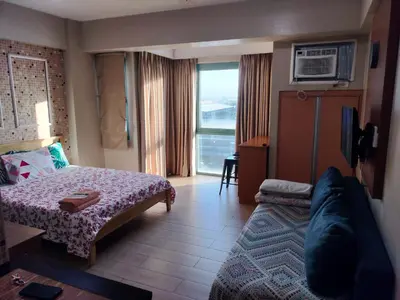 a bedroom with a bed and a couch and a window at Rqui Room Near Airport in Manila