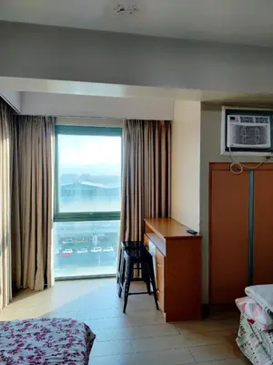 a hotel room with a bed and a desk and a window at Rqui Room Near Airport in Manila