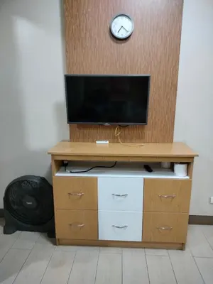 a entertainment center with a television and a clock on a wall at Rqui Room Near Airport in Manila