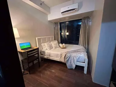 a bedroom with a bed and a desk with a laptop at AIR Residences Makati Holiday Home in Manila