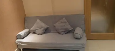a couch with three pillows on top of it at Shell Residence in Manila