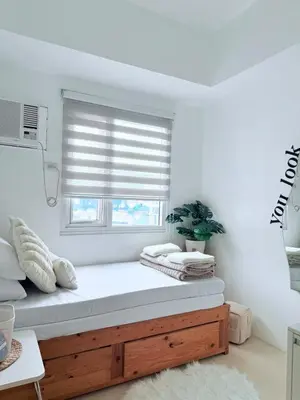 a white room with a window with a wooden bench at 42nd Floor 2BR with Stunning Views & 7 Pools in Manila