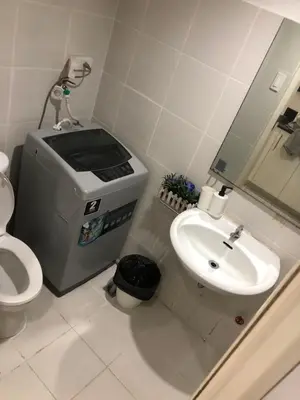 a bathroom with a toilet and a sink and a dispenser at SM MOA staycation condotel in Manila