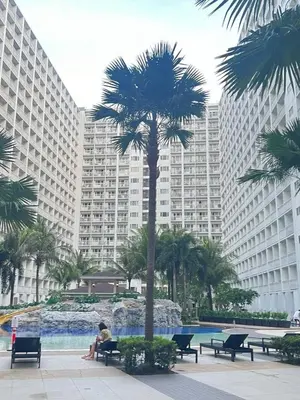 a person sitting on a bench next to a palm tree at Gracie's Suites by Staycation With FREE Parking in Manila