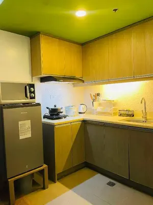 a kitchen with wooden cabinets and a refrigerator at Folks Hub in Manila