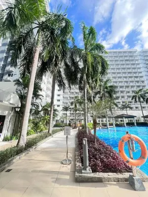 a swimming pool with palm trees and a building at Moa shell residence pasay city in Manila