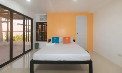 a bedroom with a bed with orange and blue pillows at Sans Hotel near Enchanted Kingdom Santa Rosa Laguna in Santa Rosa
