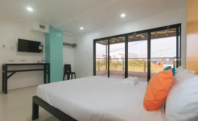 a bedroom with a bed and a desk and a window at Sans Hotel near Enchanted Kingdom Santa Rosa Laguna in Santa Rosa