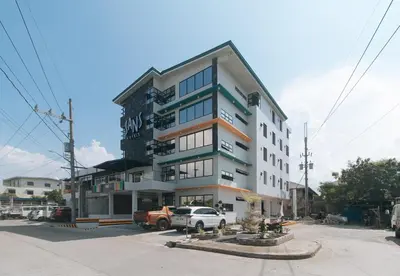 a tall building with cars parked in front of it at Sans Hotel near Enchanted Kingdom Santa Rosa Laguna in Santa Rosa