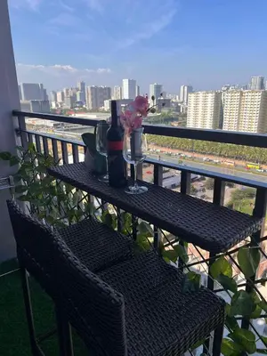 a table with a bottle of wine and flowers on a balcony at Win-Ter Staycation 1 in Manila