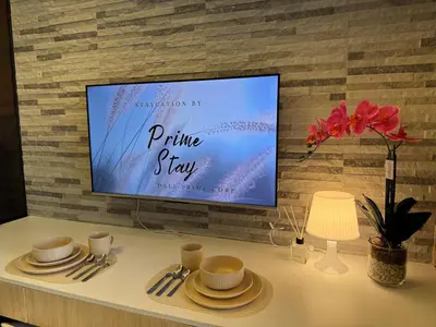 a tv on a brick wall with a table with plates and cups at Home of Mari in Shore 2 Residences Room 10107 near Airport, SM MOA, US Embassy Manila by Prime Stay MOA in Manila