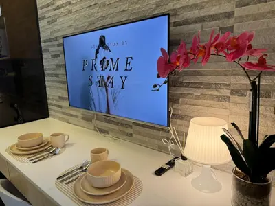 a tv screen on a wall with a table with dishes at Home of Mari in Shore 2 Residences Room 10107 near Airport, SM MOA, US Embassy Manila by Prime Stay MOA in Manila