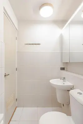 a white bathroom with a toilet and a sink at Central Modern Cosy Condo in Makati - The Linear Suite in Manila