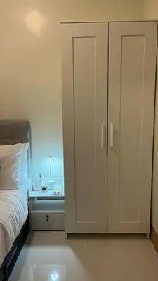 a bedroom with a white cabinet next to a bed at Modern 1-BR Retreat with Pool, High Speed Wifi, Netflix, steps from MOA, Bars, Entertainment, Transport in Manila