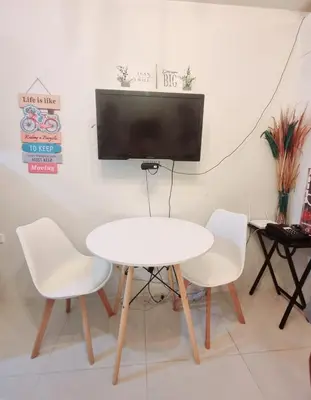 a white table and chairs with a tv on a wall at My little Apartment in Manila