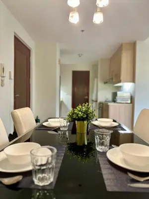 a dining table with plates and glasses and flowers on it at 1BR Corner Unit with Balcony in Manila