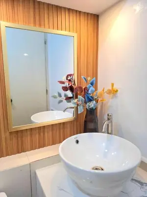 a bathroom with a white sink and a vase with flowers at 1BR with Netflix, Prime & KTV in Manila