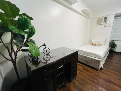 a room with a desk and a plant and a bed at Spacious 3BR with Huge TV near BGC Makati Airport in Manila