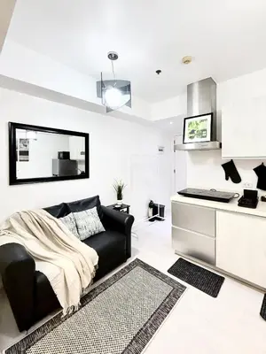 a living room with a black couch and a kitchen at Lé Boom's Staycation in Manila