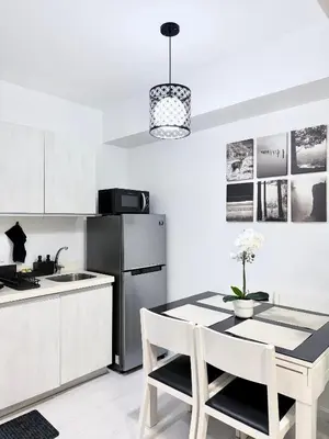 a kitchen with a table with chairs and a refrigerator at Lé Boom's Staycation in Manila
