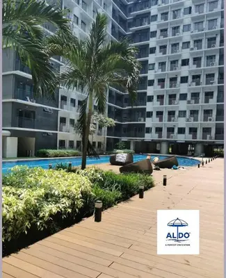 a swimming pool with palm trees and a large building at Mall of Asia condotel shore 3 residence in Manila