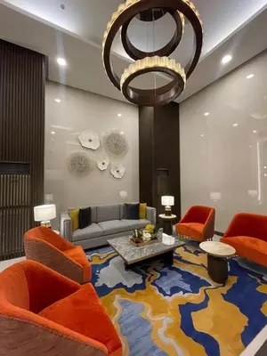 a living room with orange chairs and a large rug at Spacious 2BR near Solaire, Okada, Airport in Manila