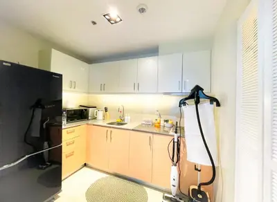 a kitchen with white cabinets and a black refrigerator at Spacious & Luxury 1BR near Solaire, Okada, Airport in Manila
