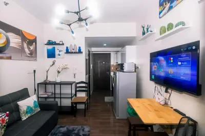 a living room with a couch and a tv on a wall at The Giggle Spot Cozy Makati Hideaway Pool & Gym 2270 in Manila