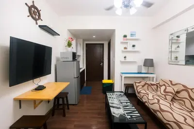 a living room with a couch and a flat screen tv at Makati MoodPad Fun Cozy Pool Access 300Mbps WiFi 2271 in Manila