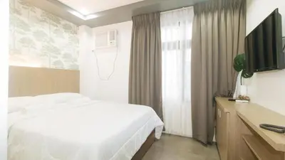 a bedroom with a white bed and a television at Gimaca Boutique Hotel in Manila